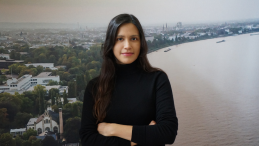 A female scientist in front of a wallpaper of the UN Bonn building on the Rhine.